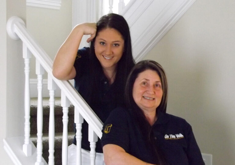 Two women posing for a photo on the stairs.