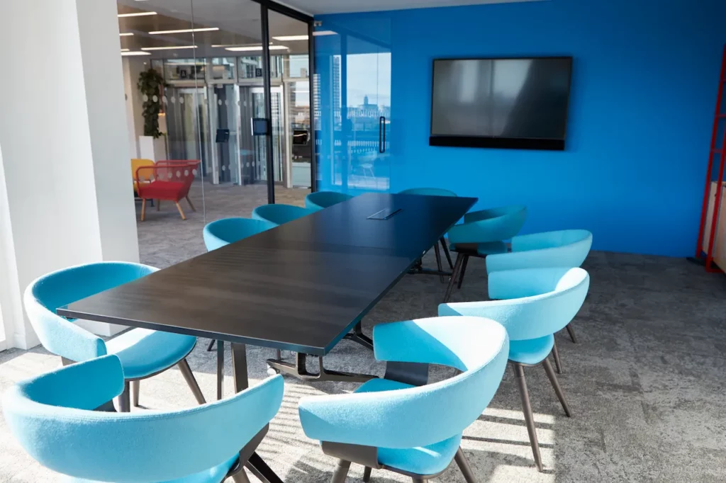 A conference room with blue chairs and a blue wall.