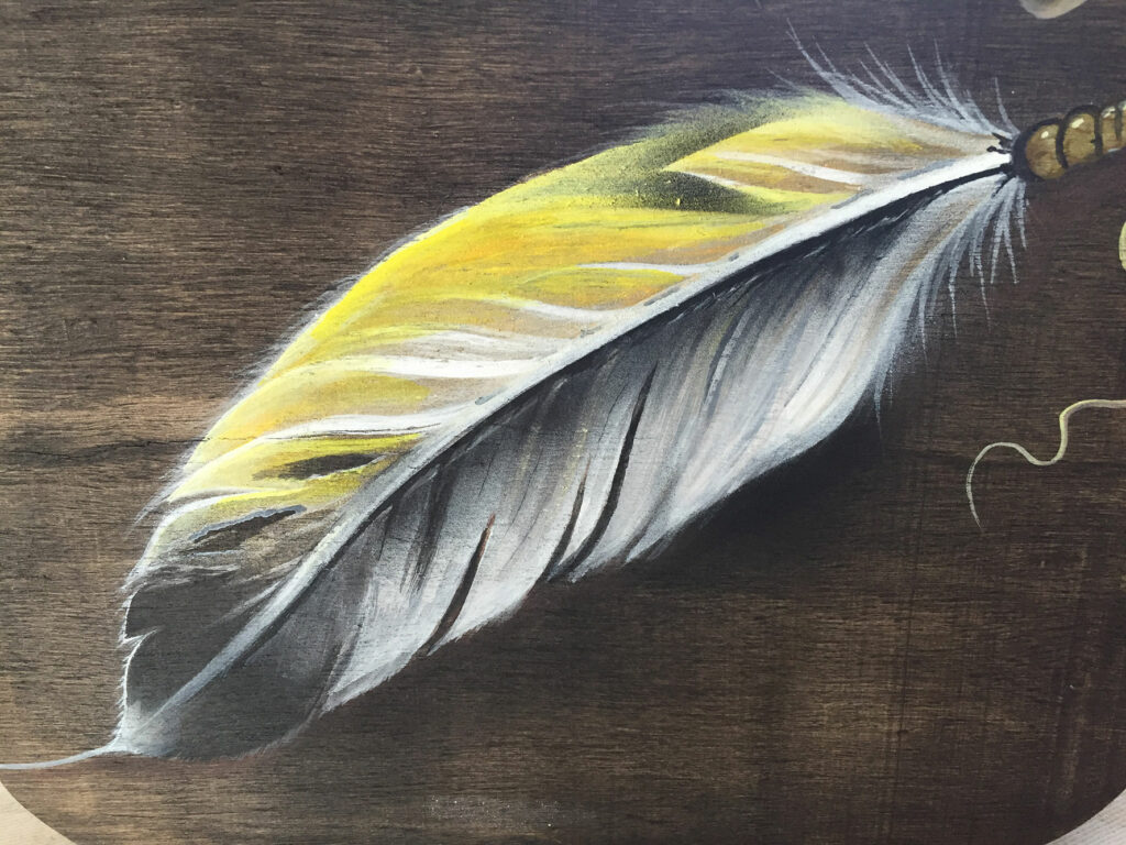 A painting of a feather on a wooden surface.