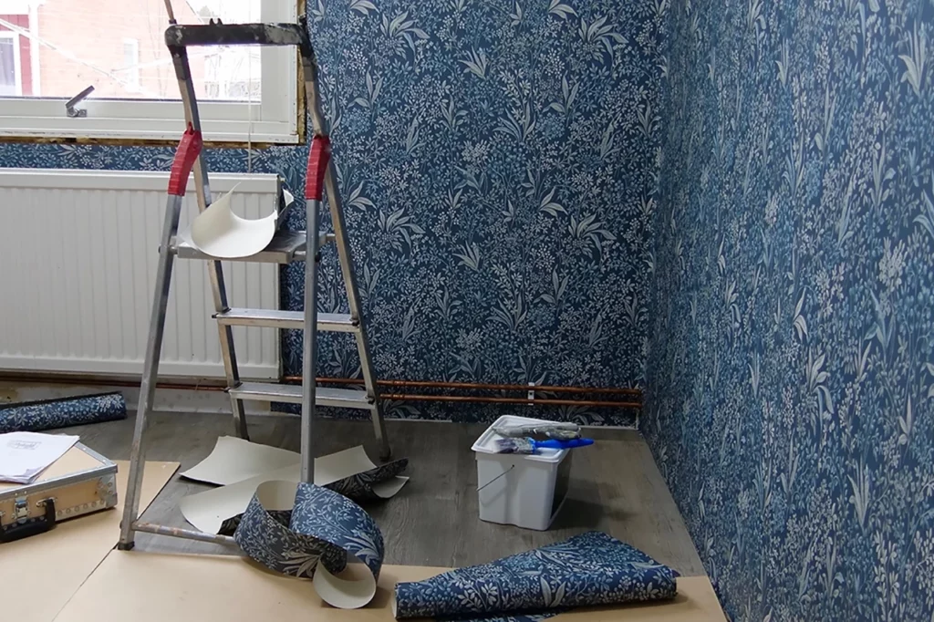 A room with blue wallpaper and a ladder.